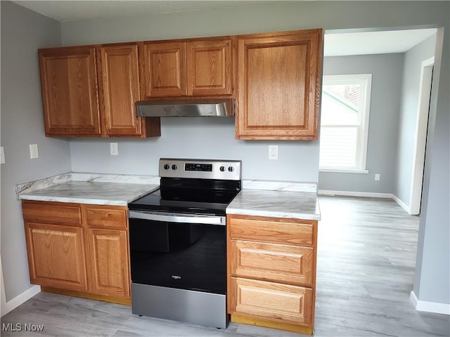 kitchen featuring stainless steel electric range, baseboards, light wood-type flooring, wall chimney exhaust hood, and light countertops
