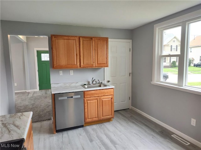 kitchen with dishwasher, a sink, light countertops, light wood-type flooring, and brown cabinets