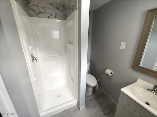 full bathroom with a stall shower, toilet, vanity, and baseboards