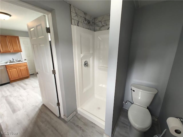 full bathroom featuring a stall shower, toilet, wood finished floors, and vanity