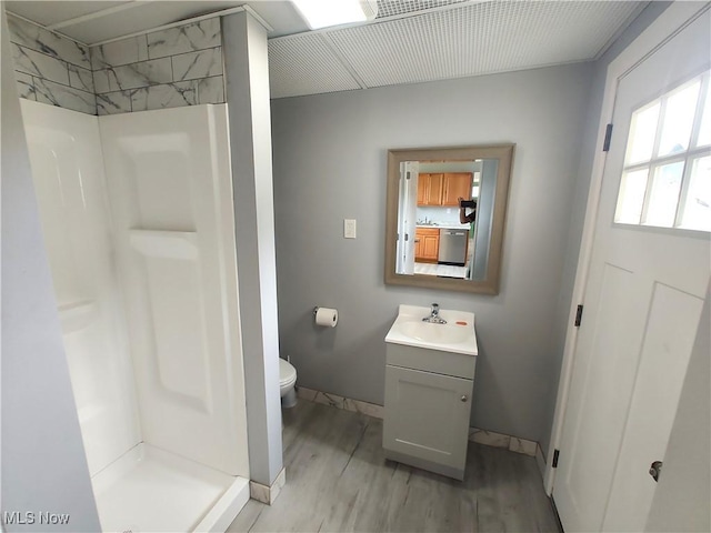 full bath with a shower stall, wood finished floors, toilet, vanity, and baseboards
