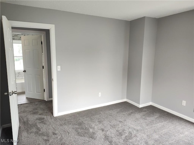 unfurnished room with carpet and baseboards