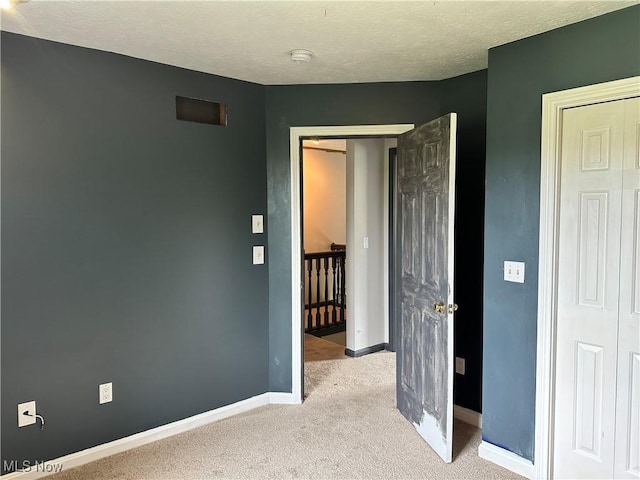 unfurnished bedroom featuring carpet, baseboards, and a textured ceiling
