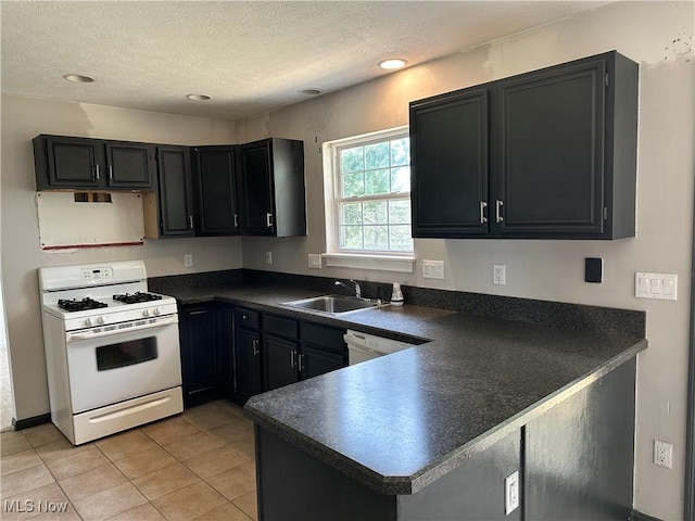 kitchen with white appliances, dark countertops, a sink, a peninsula, and light tile patterned floors