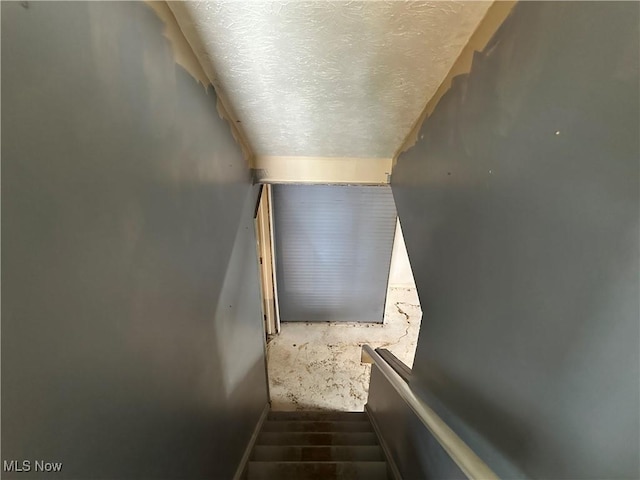 stairs with a textured ceiling