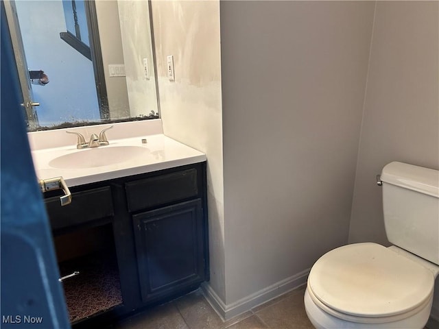 bathroom with toilet, vanity, and baseboards