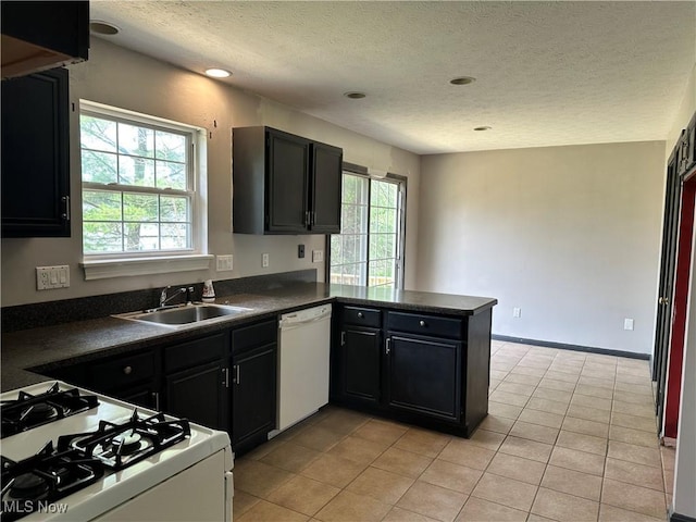 kitchen with white appliances, dark countertops, a textured ceiling, dark cabinetry, and light tile patterned flooring
