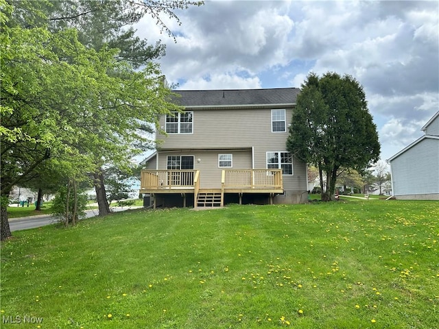 back of property with a deck and a lawn