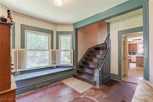 1056 Garman Rd, Akron, OH 44313 - staircase featuring plenty of natural light, brick patterned flooring, and a textured ceiling