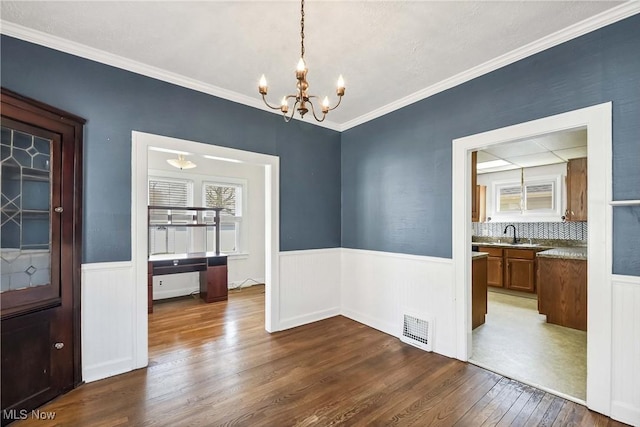 7700 Spring Garden Rd, Parma, OH 44129 - unfurnished dining area with dark wood finished floors, wainscoting, a chandelier, a sink, and ornamental molding