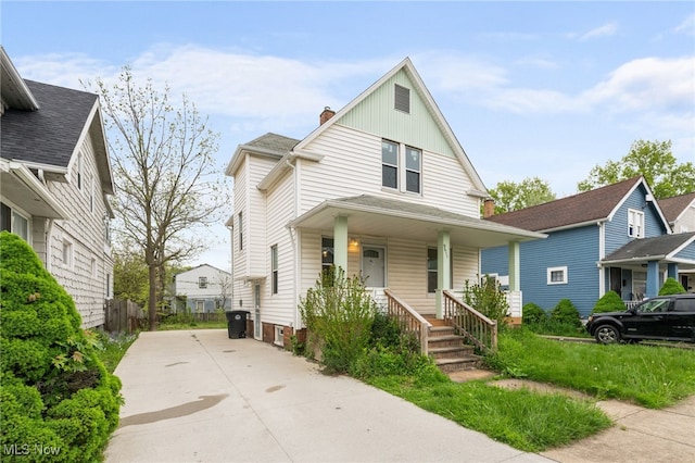 american foursquare style home with covered porch, concrete driveway, and board and batten siding