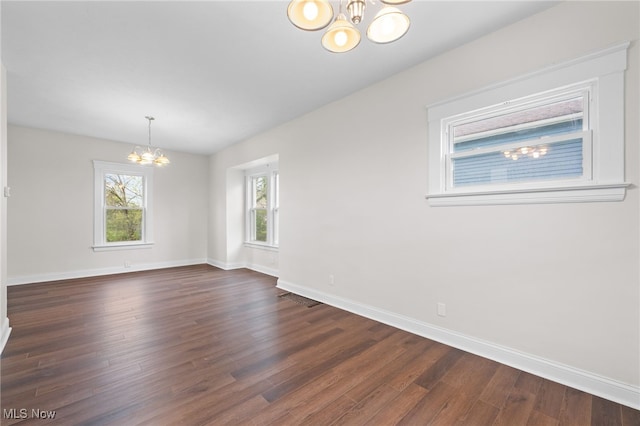 unfurnished dining area with a chandelier, dark wood-style floors, and baseboards
