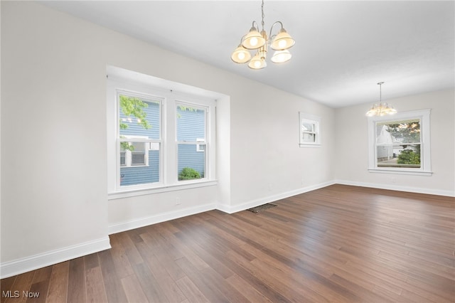 unfurnished dining area featuring a chandelier, dark wood finished floors, and baseboards
