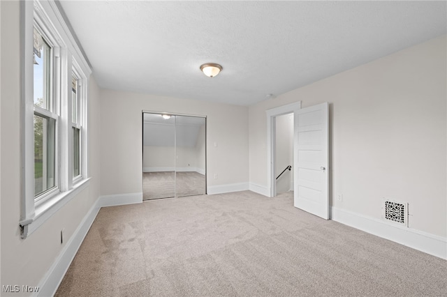 unfurnished bedroom featuring carpet floors, a closet, baseboards, and a textured ceiling