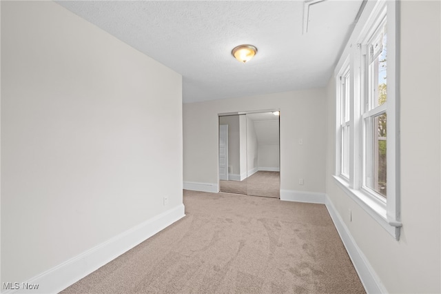 carpeted spare room with baseboards and a textured ceiling