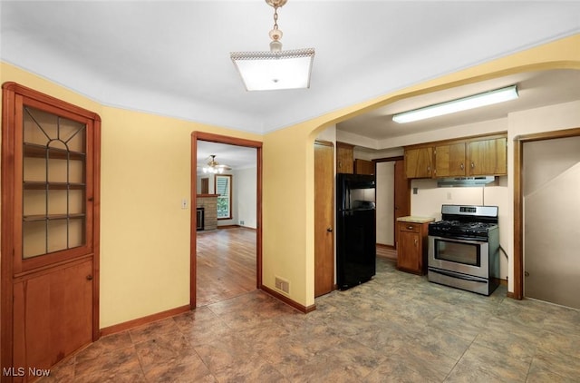 6119 E Sprague Rd, Independence, OH 44131 - kitchen with stainless steel gas range oven, freestanding refrigerator, arched walkways, and brown cabinetry