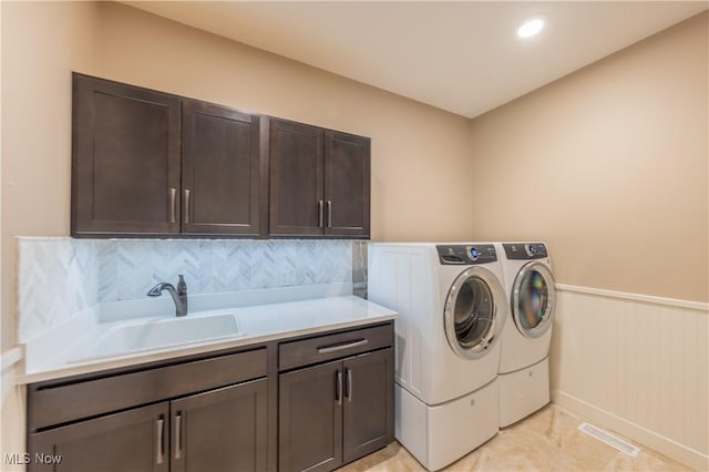 laundry area featuring cabinet space, separate washer and dryer, and a wainscoted wall