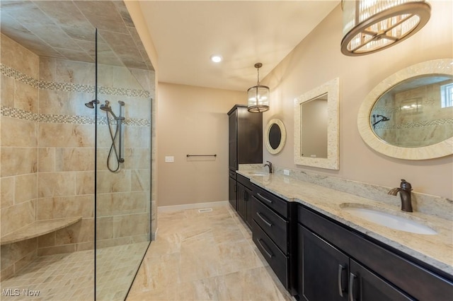 bathroom featuring a walk in shower, double vanity, and baseboards