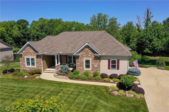 view of front of home with stone siding, covered porch, a front lawn, and roof with shingles