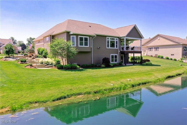 rear view of property with a balcony, a lawn, and a water view