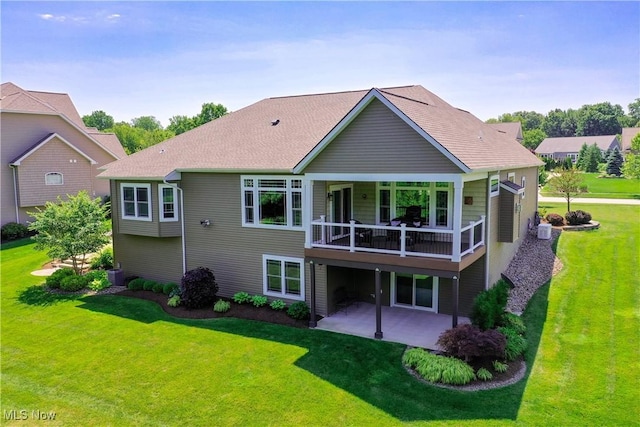 rear view of house featuring a patio, a lawn, a balcony, cooling unit, and roof with shingles