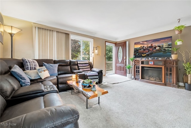 carpeted living room featuring a glass covered fireplace