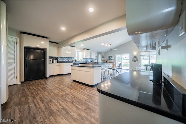 24660 Sittingbourne Ln, Beachwood, OH 44122 - kitchen with freestanding refrigerator, dark countertops, dark wood finished floors, white cabinets, and lofted ceiling