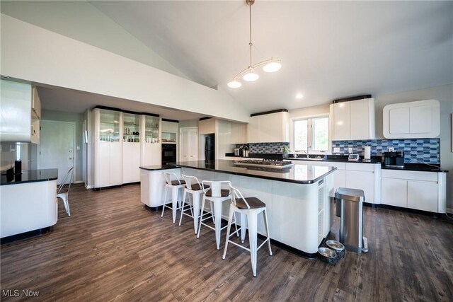24660 Sittingbourne Ln, Beachwood, OH 44122 - kitchen with tasteful backsplash, dark wood-style floors, white cabinets, dark countertops, and lofted ceiling