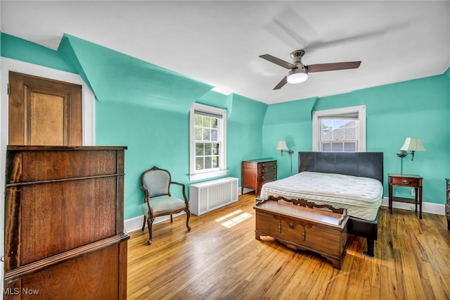 bedroom with radiator, hardwood / wood-style floors, baseboards, and a ceiling fan