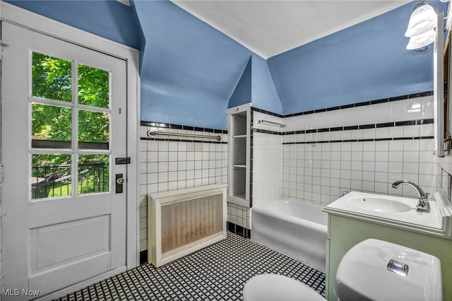 bathroom with tile walls, a sink, healthy amount of natural light, a bath, and radiator heating unit