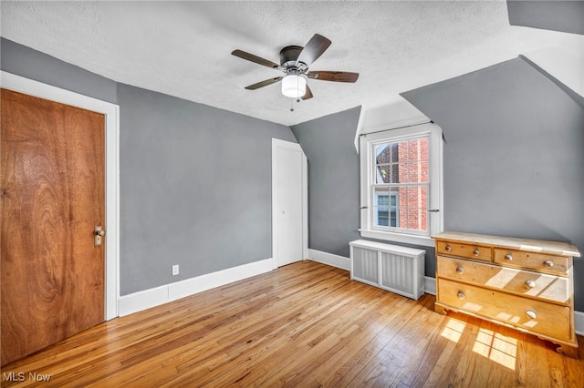 bonus room featuring hardwood / wood-style floors, a textured ceiling, radiator, baseboards, and a ceiling fan