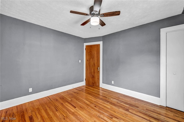 empty room with hardwood / wood-style floors, a textured ceiling, baseboards, and ceiling fan