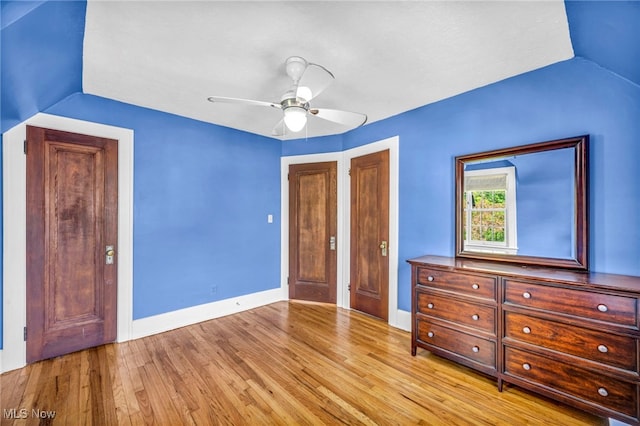 unfurnished bedroom featuring wood finished floors, baseboards, ceiling fan, and vaulted ceiling