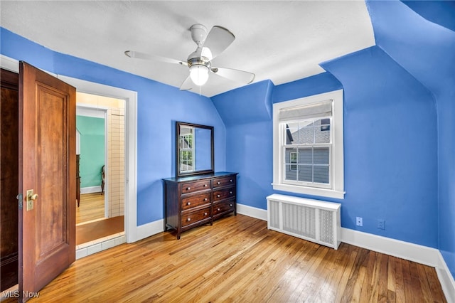 bedroom featuring radiator heating unit, lofted ceiling, light wood-type flooring, baseboards, and a ceiling fan