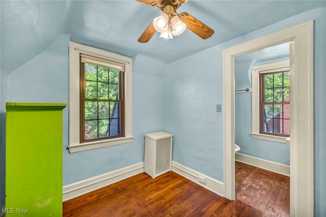 additional living space with wood-type flooring, vaulted ceiling, healthy amount of natural light, ceiling fan, and baseboards