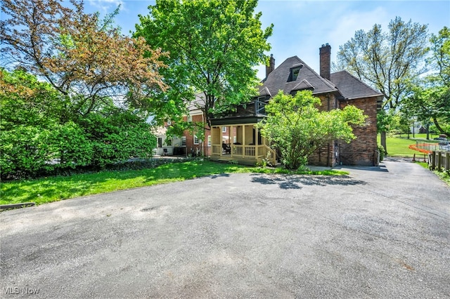 view of front of house featuring a porch, a chimney, and a front lawn