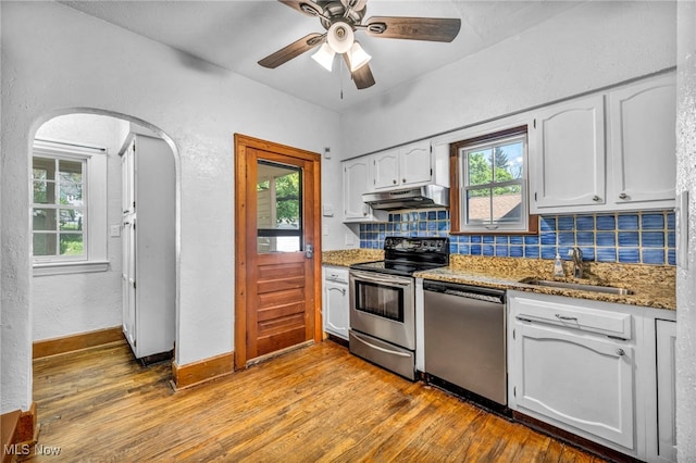 kitchen with stainless steel appliances, a sink, under cabinet range hood, backsplash, and white cabinets