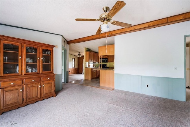 9493 State Route 9, Hanoverton, OH 44423 - unfurnished living room featuring ceiling fan, light colored carpet, a wainscoted wall, beam ceiling, and wood walls