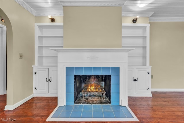 detailed view of built in features, crown molding, wood finished floors, arched walkways, and baseboards