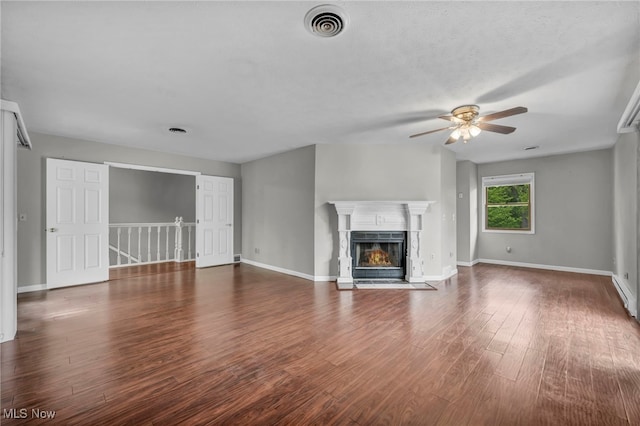 unfurnished living room featuring a ceiling fan, a premium fireplace, wood finished floors, and baseboards