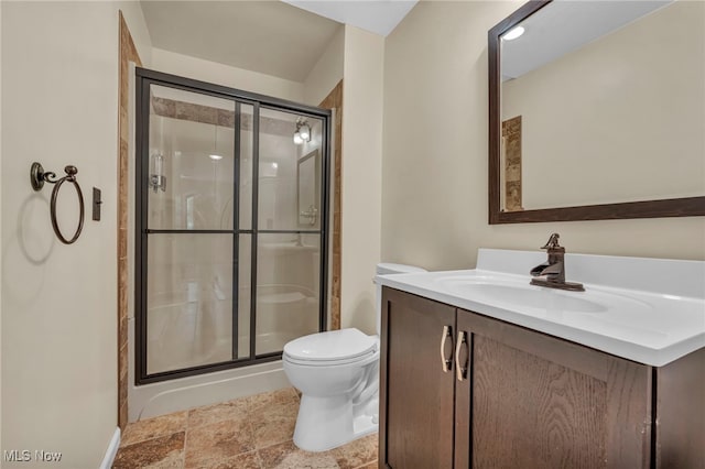 bathroom featuring a stall shower, toilet, vanity, and stone finish flooring