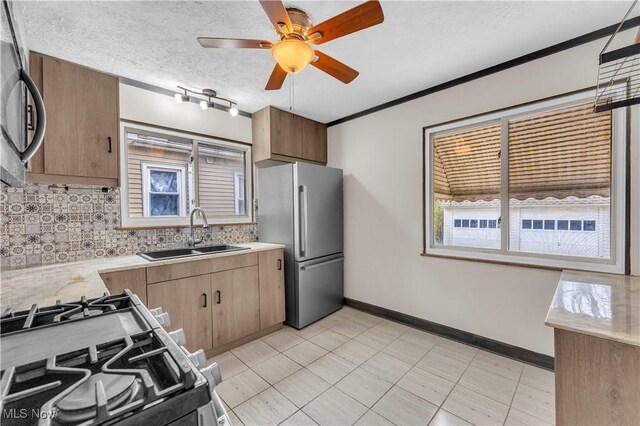kitchen featuring a sink, freestanding refrigerator, light countertops, gas range oven, and tasteful backsplash