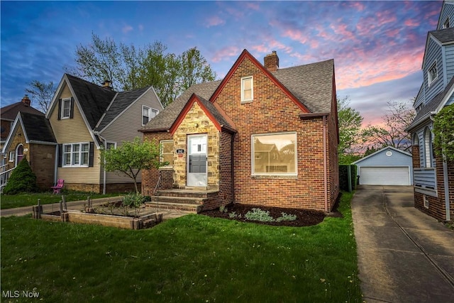 tudor home featuring an outbuilding, a front yard, a detached garage, a chimney, and brick siding