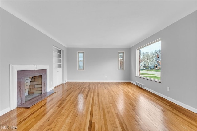 unfurnished living room featuring light wood-style floors, built in features, and baseboards
