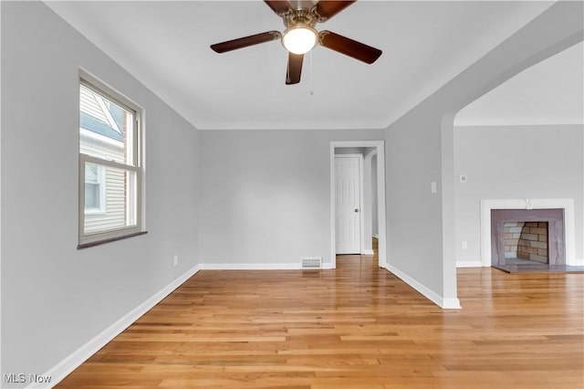 unfurnished living room featuring baseboards, light wood-style flooring, ceiling fan, and a fireplace