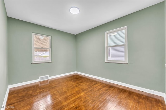 spare room featuring wood-type flooring and baseboards
