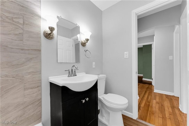 bathroom featuring wood finished floors, vanity, toilet, and baseboards