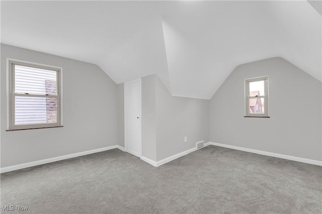 additional living space with carpet flooring, vaulted ceiling, and baseboards