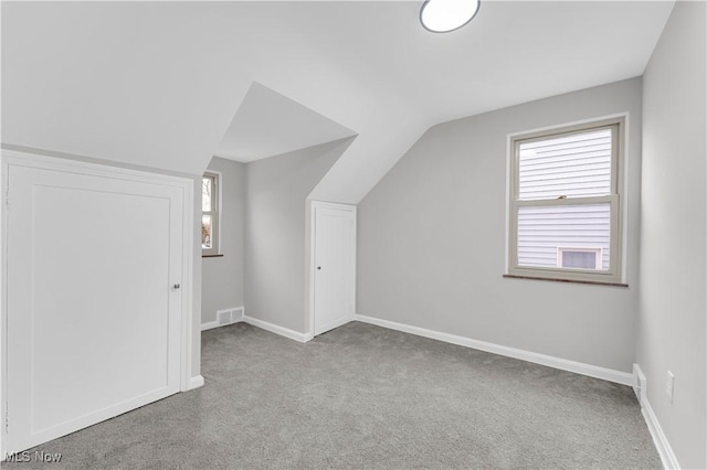 bonus room with carpet floors, vaulted ceiling, baseboards, and plenty of natural light