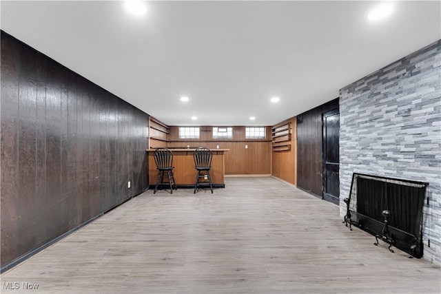 office area with wood walls, a bar, light wood-type flooring, a fireplace, and recessed lighting
